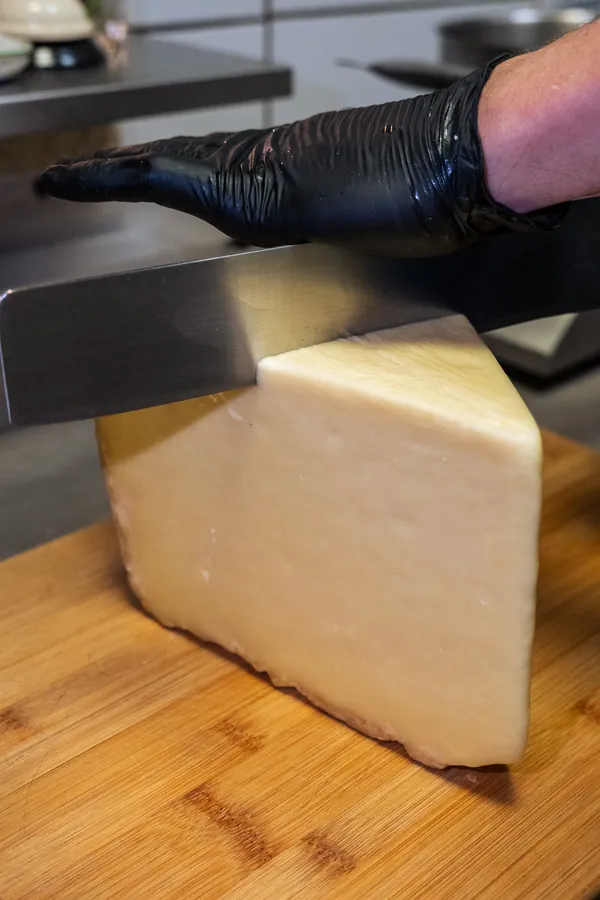 Découpe du comté à la main en cuisine, Chez Magda